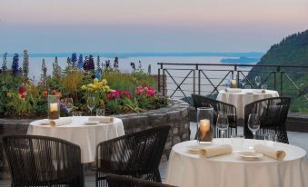 an outdoor dining area with tables and chairs set up on a rooftop patio , overlooking the ocean at Lefay Resort & Spa Lago di Garda