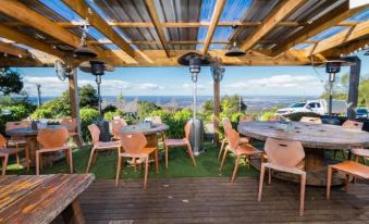 an outdoor dining area with wooden tables and chairs , surrounded by a grassy area and overlooking a beautiful view of the mountains at Archibald Hotel