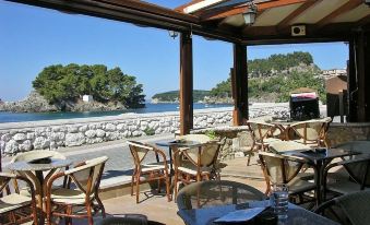 a picturesque outdoor dining area with a view of the sea , where several people are enjoying their meals at Utopia