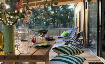 a wooden table with a green and white striped pillow on it , surrounded by several chairs on a porch at Green Resort