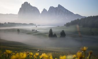 a serene landscape of a valley with mountains in the background and yellow flowers in the foreground at Romantik Hotel Turm