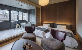 a modern bedroom with two beds , a coffee table , and a large window overlooking a hot tub at Zazan Minakami