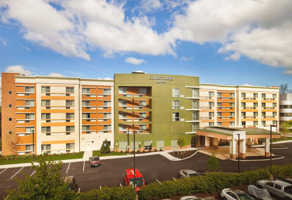 a large hotel with multiple stories , located in a city with green and orange accents at Courtyard Yonkers Westchester County