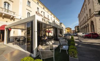 a hotel with a patio area featuring lounge chairs and umbrellas , as well as tables and chairs for guests at Sina Brufani