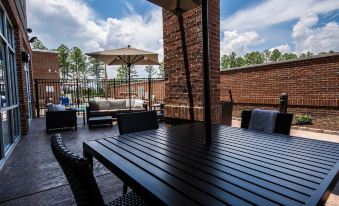 a wooden patio set with a table and chairs , an umbrella , and a brick wall at Courtyard Columbia Cayce