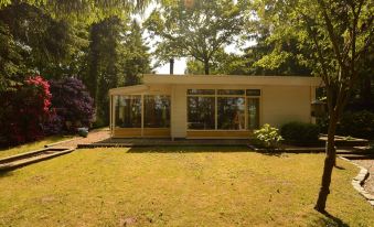 A Detached Bungalow with Outdoor Fireplace Covered Terrace and Pond in a Forest Plot