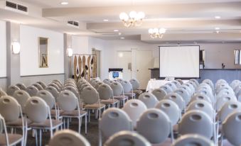 a large conference room with rows of chairs arranged in a semicircle , and a projector screen on the wall at Tamar Valley Resort Grindelwald