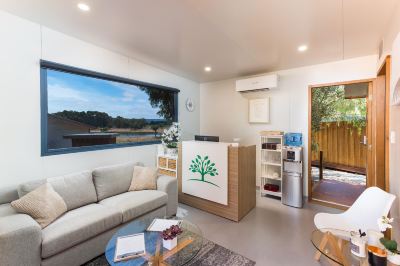 a modern living room with a couch , coffee table , and a large window overlooking a field at The Swan Valley Retreat