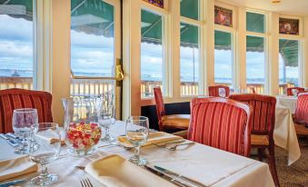 a restaurant table is set with white tablecloths , silverware , and wine glasses in front of a window at Club Wyndham Bay Voyage Inn