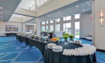 a long table with a black tablecloth is set up in a room with large windows at Embassy Suites by Hilton Plainfield Indianapolis Airport