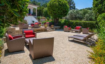 a courtyard with several chairs and couches arranged for outdoor relaxation , surrounded by trees and a house at Boutique Hotel Ilio