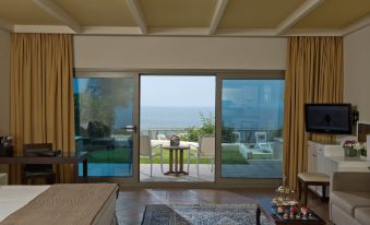 a bedroom with a view of the ocean through a glass door , featuring a bed and curtains at Le Royal Hotel - Beirut