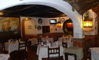 a restaurant with tables and chairs , a tv on the wall , and various decorations on the walls at Hotel Posada del Hidalgo