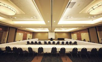 a large conference room with multiple rows of tables and chairs , a projector screen , and recessed lighting at Jackpot Junction Casino Hotel