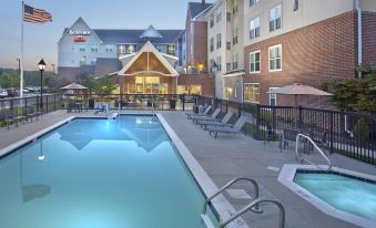 a large outdoor swimming pool surrounded by multiple buildings , with people enjoying their time in the pool area at Residence Inn Waldorf
