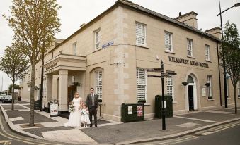 a bride and groom posing for a picture in front of an old stone building at Kilmorey Arms Hotel