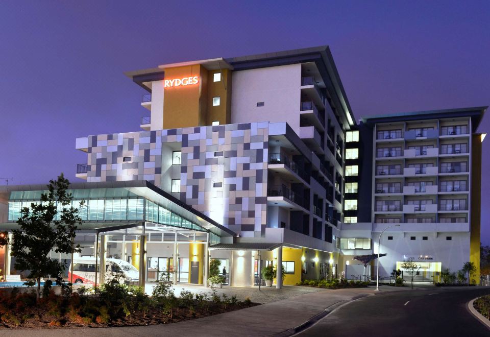 "a large hotel building with a red sign that says "" tryges "" is surrounded by cars and trees" at Rydges Palmerston - Darwin, an EVT hotel