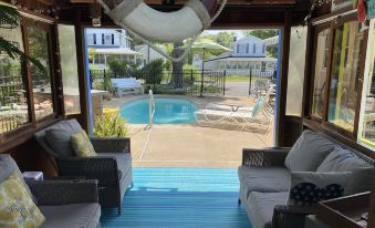 a cozy outdoor living area with a pool , surrounded by white furniture and a blue carpet at Colonial Beach Plaza Bed & Breakfast