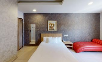 a large bed with white sheets and a red bench in the corner of a room at Era Plus Hotel