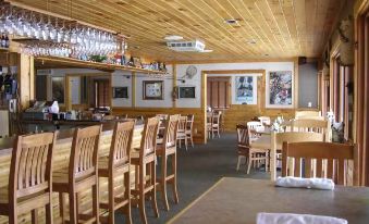a large dining room with wooden furniture , including tables and chairs , and a long bar area at Sugar Lake Lodge