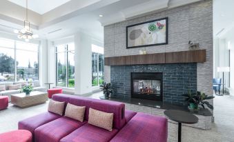 a large , modern living room with a purple couch and a fireplace , creating a cozy atmosphere at Hilton Garden Inn Gilroy