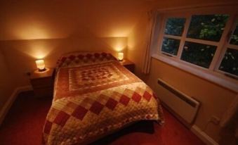 a cozy bedroom with a large bed and two lamps , creating a warm and inviting atmosphere at The Hatchet Inn
