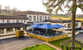 a building with a large blue umbrella in front of it , surrounded by green grass and trees at Springfield Hotel and Restaurant