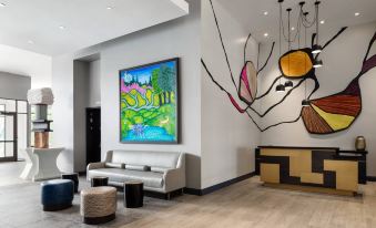 a modern hotel lobby with white walls , wooden floors , and a large painting on the wall at The MC Hotel, Autograph Collection