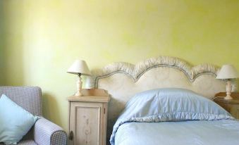 a bedroom with a bed , nightstand , and lamp , decorated in white and blue colors against a yellow wall at Stone House