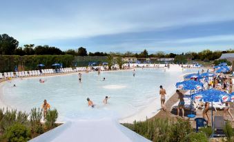 a large outdoor swimming pool with people enjoying the water and sun loungers around it at Hu Montescudaio Village
