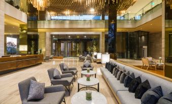 a modern hotel lobby with a large chandelier , several couches , and several potted plants at Arize Hotel Sri Racha