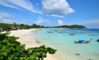 a beautiful tropical beach with clear blue water , white sand , and several boats anchored in the bay at Chareena Hill Beach Resort