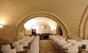 a large room with rows of white chairs arranged in a semicircle , likely for a conference or meeting at Castello di Semivicoli