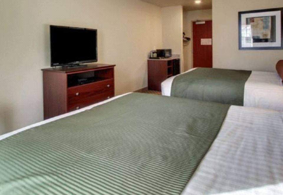 a hotel room with two beds , a tv , and a desk , all neatly arranged in the space at Cobblestone Hotel & Suites - Erie
