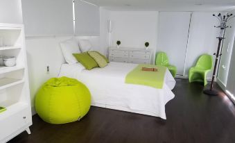 a modern bedroom with white walls , hardwood floors , and a large bed decorated with green accents at Modern Cabins
