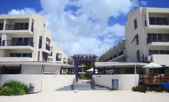 a residential area with white buildings and a blue gate , under a cloudy sky with scattered clouds at Infinity on the Beach