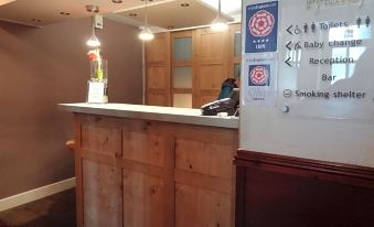 "a reception area with a wooden counter and a sign on the wall that says "" smoke free "" and "" no smoking .""." at The Pytchley Inn