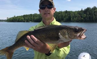 a man in a green shirt is holding a large fish while standing on a boat at Kohl's Resort