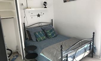 a small bedroom with a bed , a chair , and a tv . the walls are white and the room has a black metal headboard at Marina