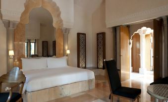 The elegant room features a large white bed, a marble countertop, and a wooden framed door at Amanbagh
