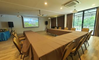 a conference room with a large table surrounded by chairs and a projector screen on the wall at Phuphayot Resort