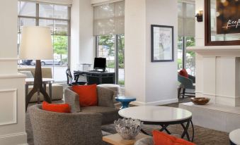 a modern living room with large windows , gray sofas , and red pillows , creating a cozy and inviting atmosphere at Hilton Garden Inn Kent Island