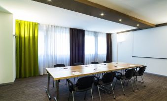 a conference room with a long table , chairs , and green curtains , set up for a meeting at Mercure Milano Agrate Brianza