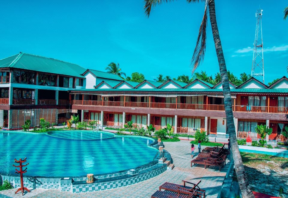 a large hotel with a swimming pool surrounded by palm trees and a clear blue sky at Holiday Inn Beach Resort