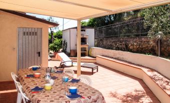 a patio with a dining table and chairs set up for a meal , surrounded by a lush garden at Cristina