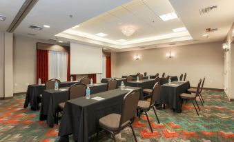 a conference room with several tables and chairs arranged for a meeting or event , along with a projector screen at Hilton Garden Inn Nanuet