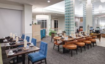 a modern , well - lit dining area with wooden tables and chairs arranged in a semi - circle at Hilton Garden Inn Hilton Head