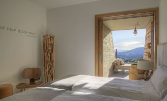 a bedroom with two beds , a wooden chair , and a window overlooking a mountainous landscape at Trossos del Priorat