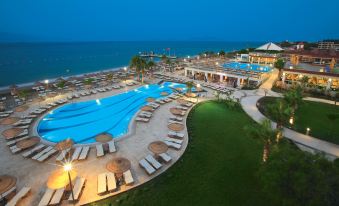 a large resort with a pool and surrounding beach area at night , illuminated by lights at Armonia Holiday Village & Spa