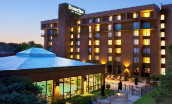 a large hotel with a pool in front of it and outdoor seating areas around the pool at DoubleTree by Hilton Hotel Syracuse